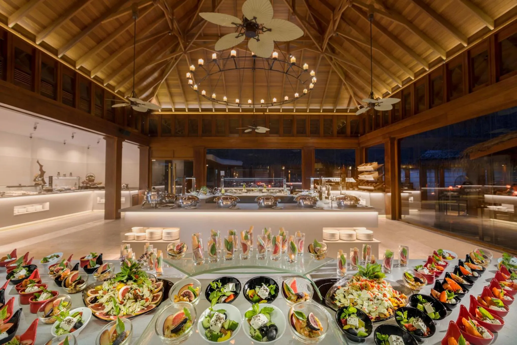 Un buffet de plats variés est présenté dans une salle à manger ouverte sur l'extérieur.