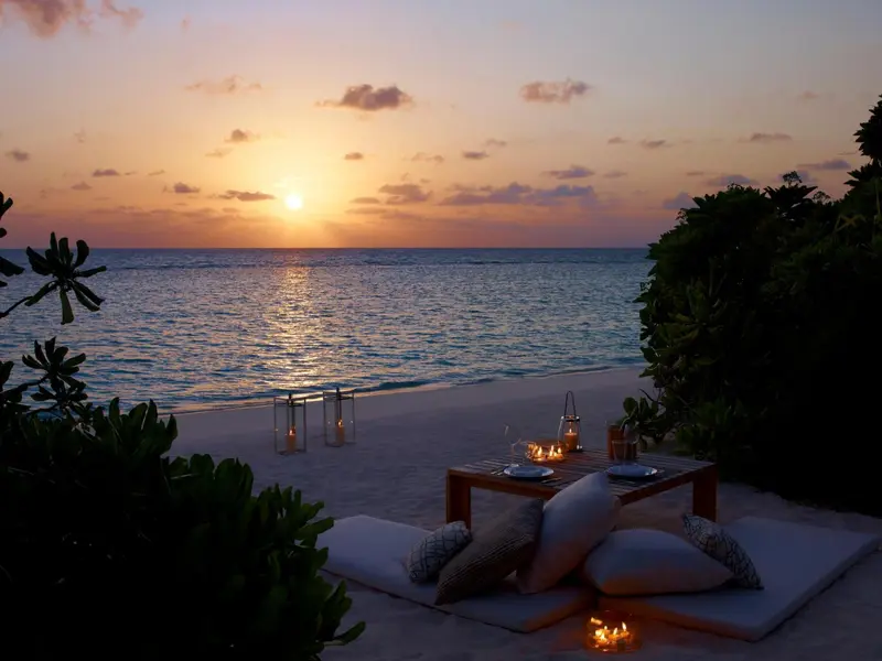 Une table dressée sur le sable au coucher du soleil.