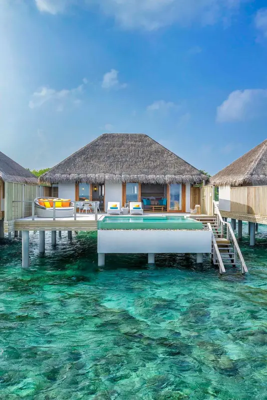 Villa sur pilotis avec piscine privée et accès direct à l'eau turquoise.
