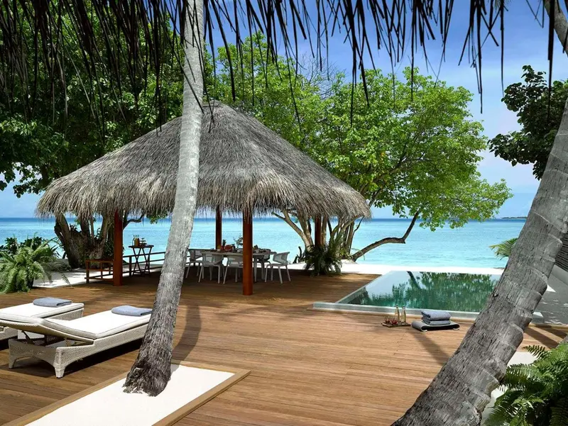Terrasse en bois avec chaises longues, piscine et cabane de plage.