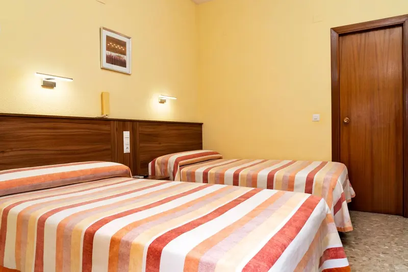 Chambre avec deux lits simples et des lampes murales.