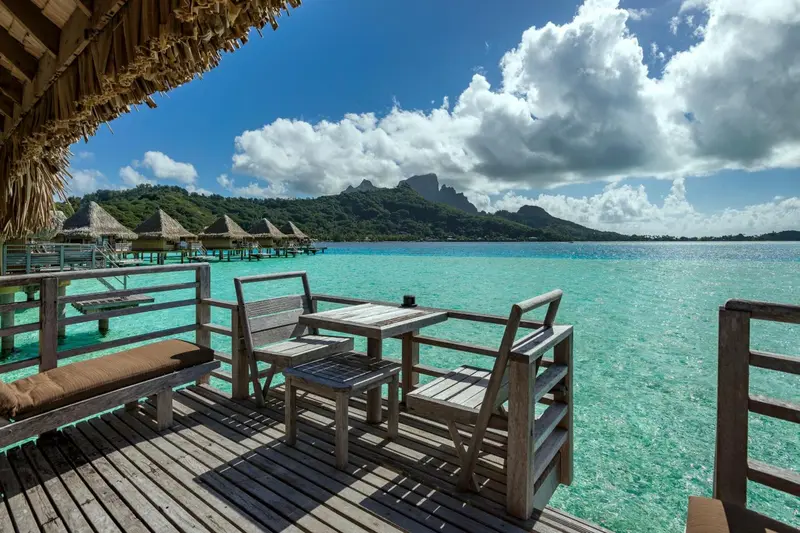 Terrasse en bois avec mobilier de jardin donnant sur une eau turquoise et des îles verdoyantes.