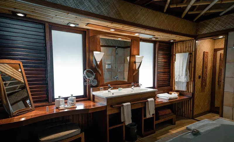 Une salle de bain lumineuse avec deux vasques et un grand miroir.