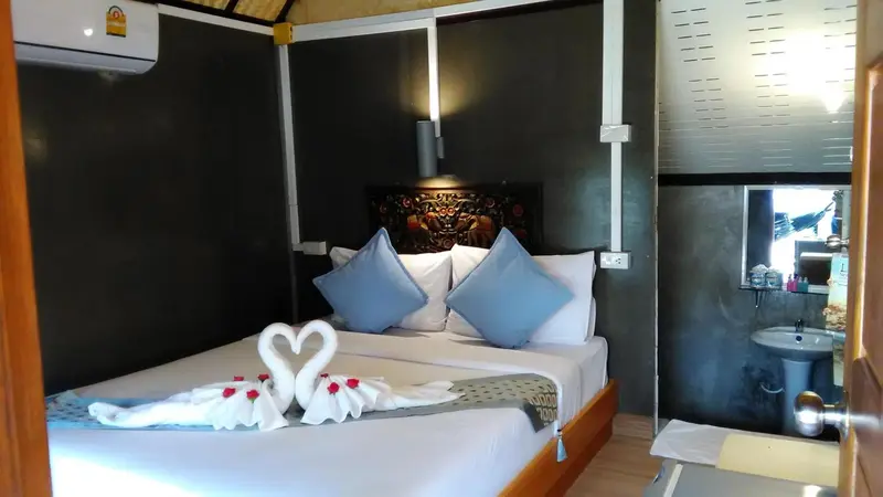 Une chambre avec un grand lit décoré de serviettes en forme de cygnes.