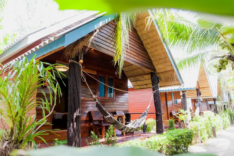 Un bungalow en bois avec un hamac sur la terrasse.