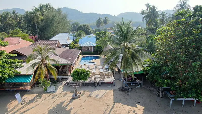 Vue aérienne d'un complexe hôtelier avec piscine et végétation tropicale.