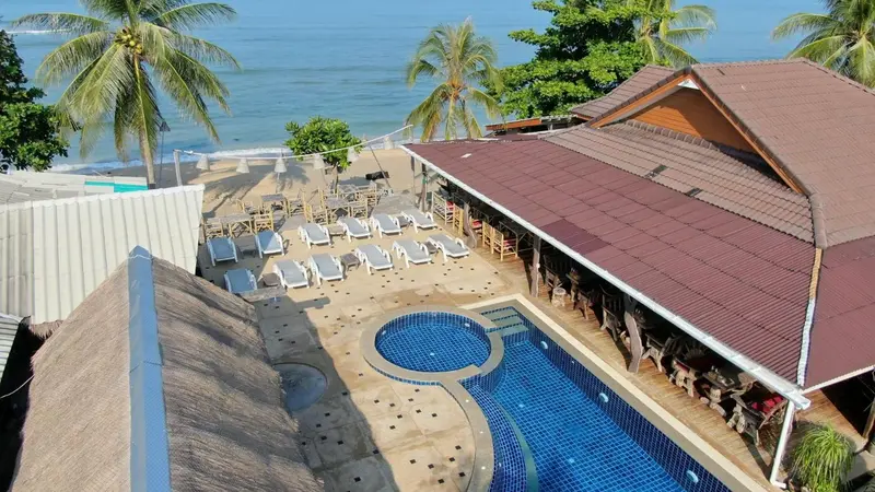 Vue aérienne d'une piscine et d'une plage bordée de palmiers.