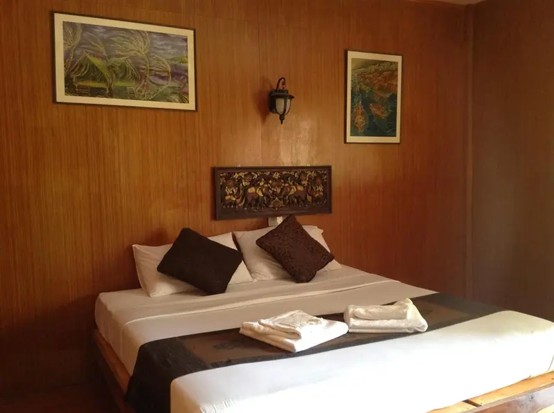 Une chambre avec un grand lit recouvert d'une courtepointe blanche et de coussins.