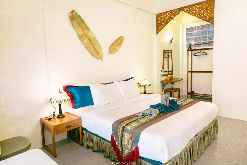 Une chambre lumineuse avec un grand lit recouvert d'une courtepointe colorée et de coussins.