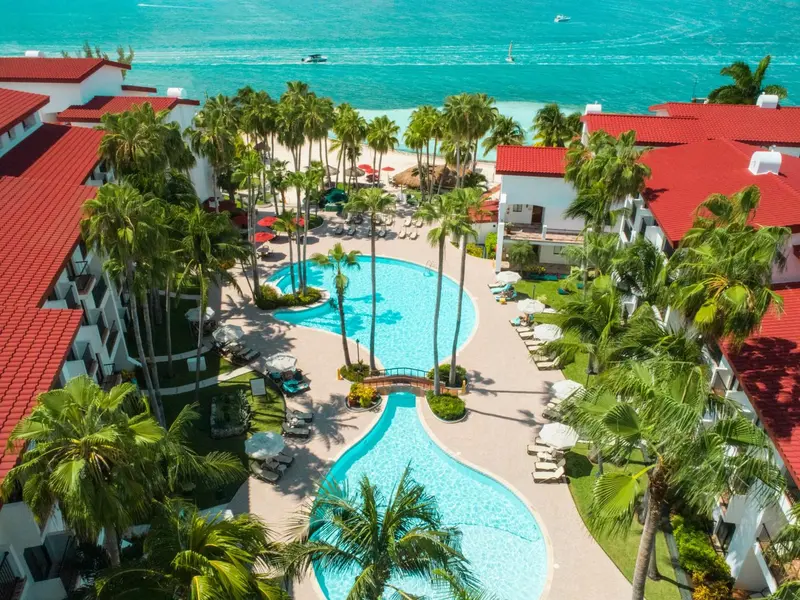Vue aérienne d'un complexe hôtelier avec des piscines et une plage.