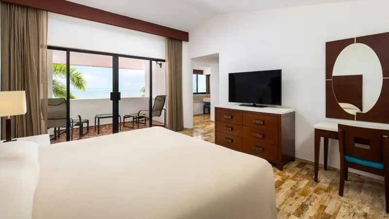 Une chambre lumineuse avec un grand lit et un accès à une terrasse vue sur mer.