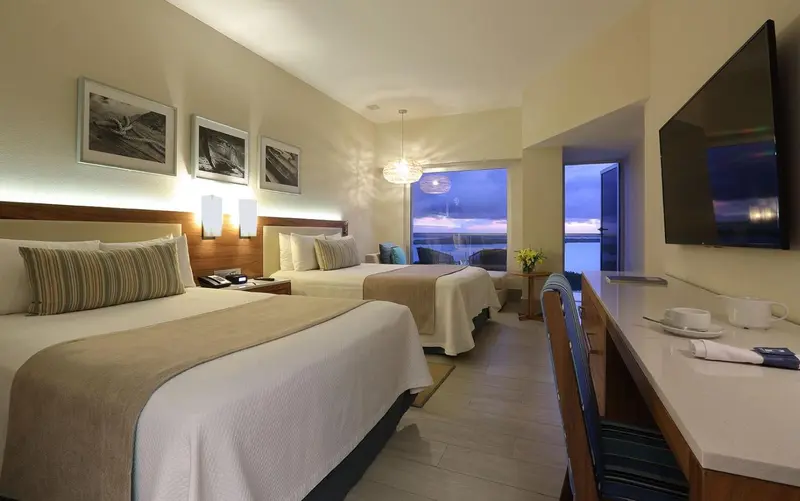 Chambre lumineuse avec deux lits et vue sur la mer.