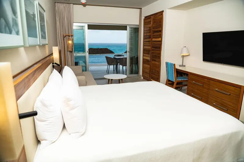 Une chambre lumineuse avec un grand lit et une vue sur la mer.