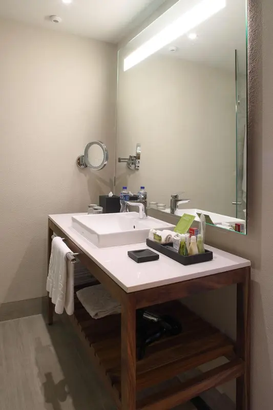 Une salle de bain moderne avec un grand miroir et des serviettes.