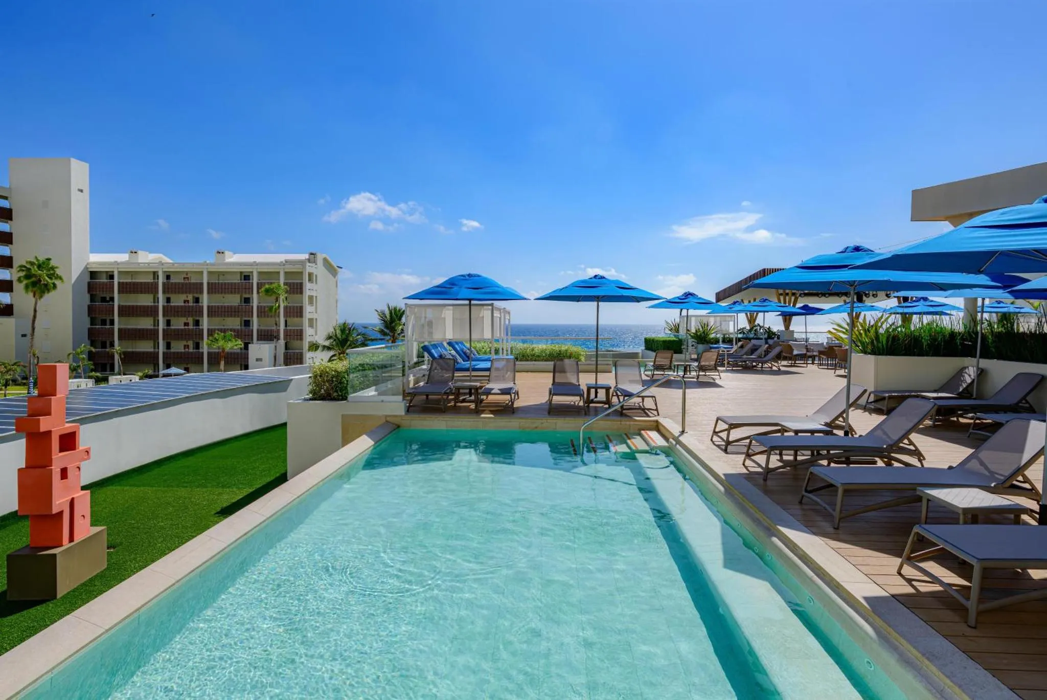 Terrasse avec piscine et transats face à la mer.