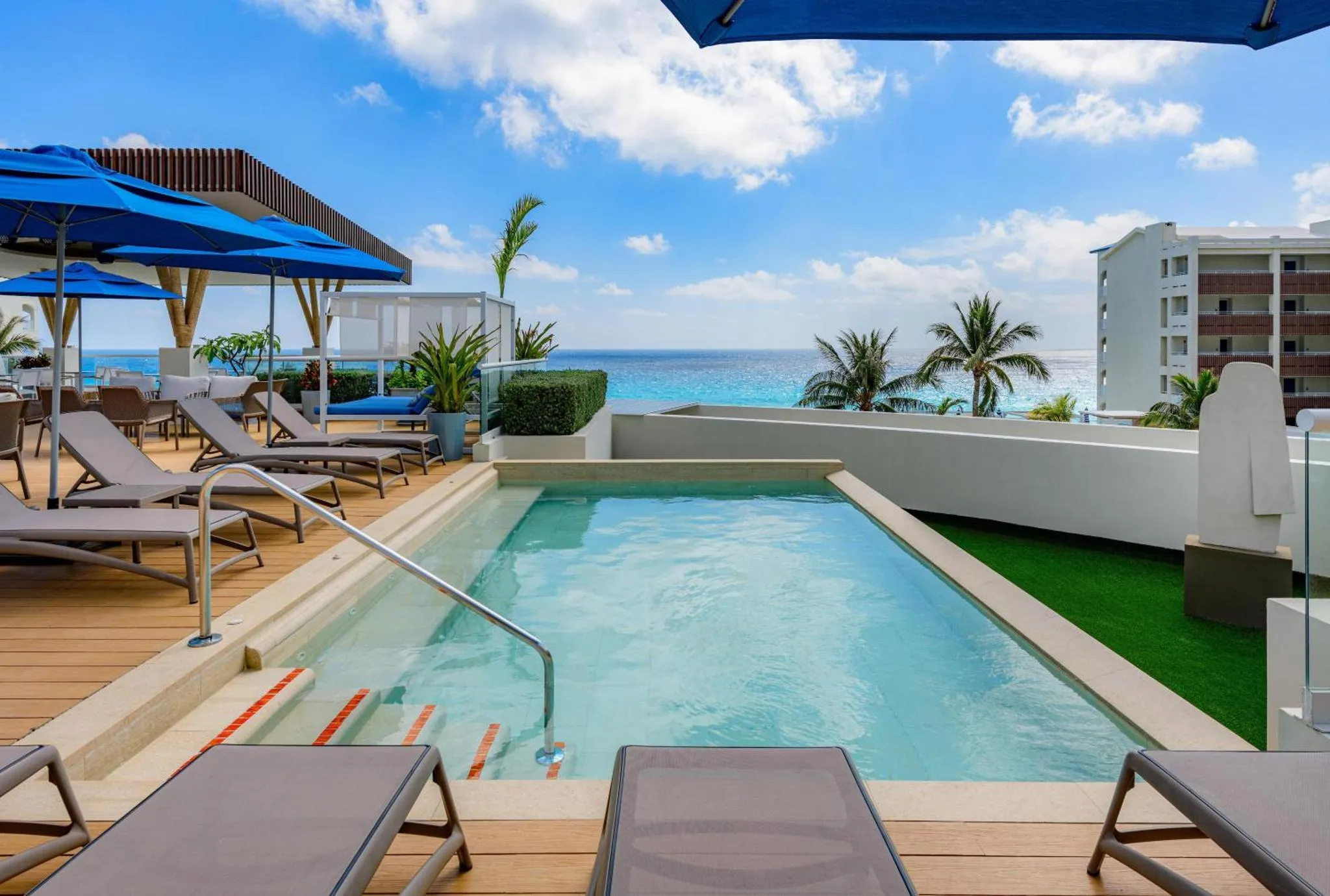 Transats et petite piscine sur une terrasse ensoleillée avec vue sur la mer.