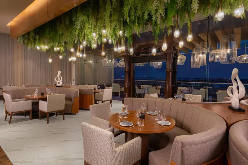 Une salle de restaurant élégante avec des tables dressées et une vue sur la mer.