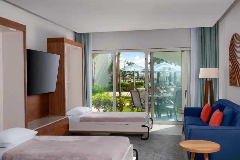 Une chambre lumineuse avec un lit, un canapé et un accès à une terrasse.