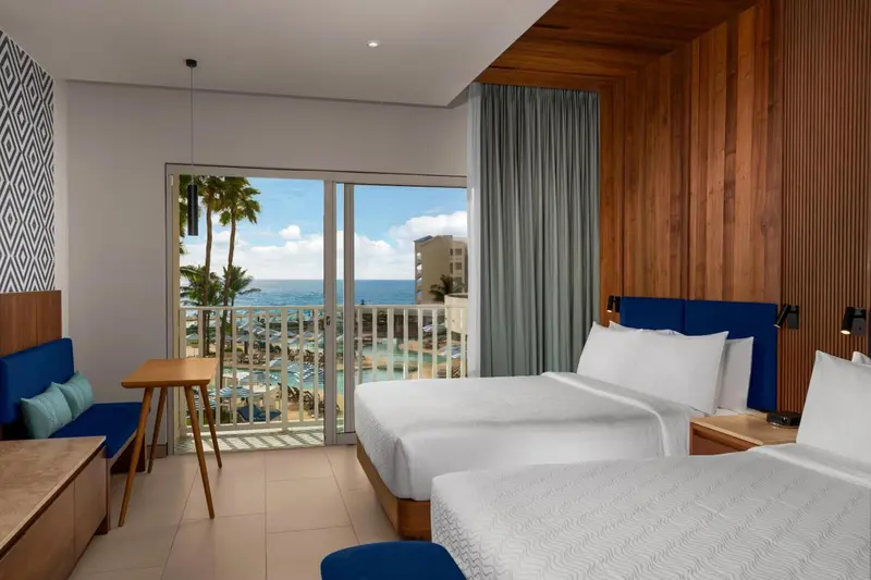 Chambre lumineuse avec vue sur la mer et les palmiers.