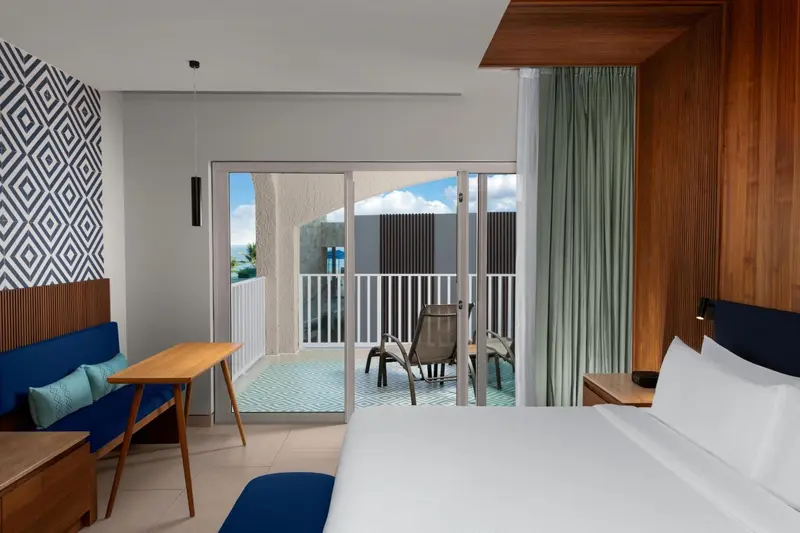 Une chambre lumineuse s'ouvre sur un balcon avec mobilier d'extérieur.