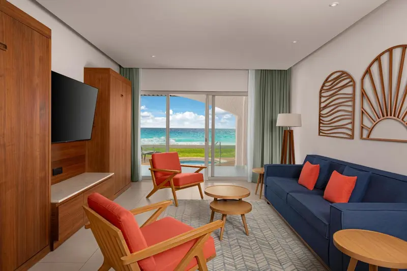 Espace de vie lumineux avec canapés et fauteuils face à une vue sur la mer.