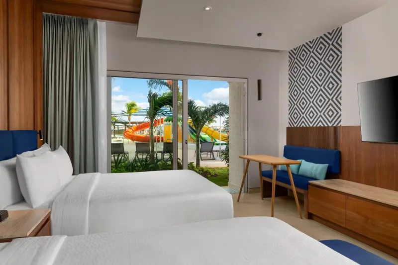 Chambre lumineuse avec lits jumeaux donnant sur une vue tropicale.