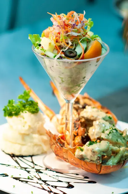 Présentation raffinée d'un plat de fruits de mer avec une salade et une sauce crémeuse.