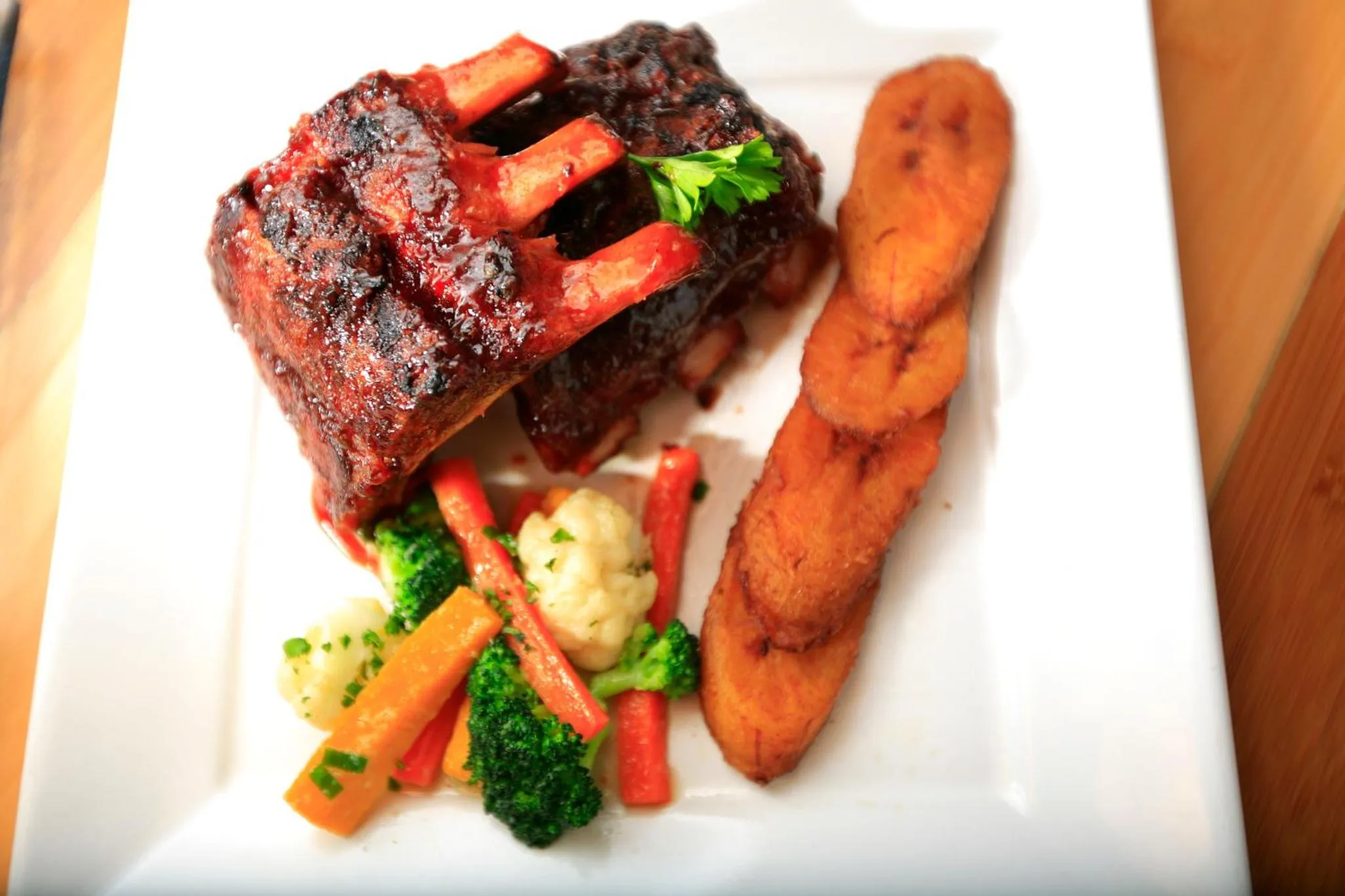 Assiette de viande grillée accompagnée de légumes et de bananes plantains.