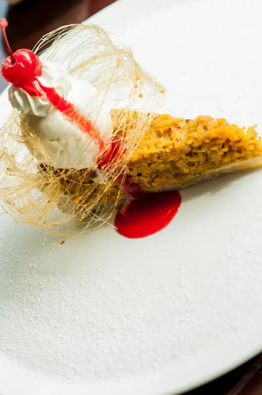 Une part de gâteau à la crème et aux fruits rouges est présentée sur une assiette blanche.