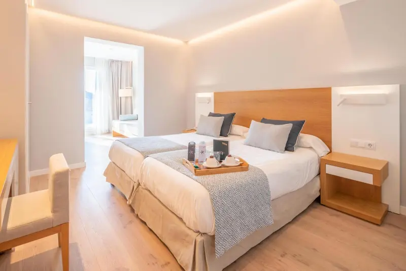 Une chambre lumineuse avec un grand lit et une table de chevet.