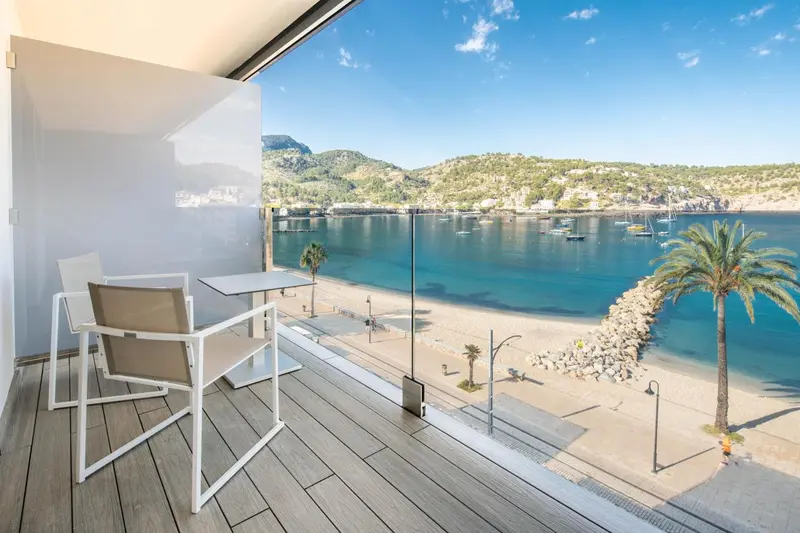 Une terrasse aménagée offre une vue sur une plage et une baie ensoleillée.