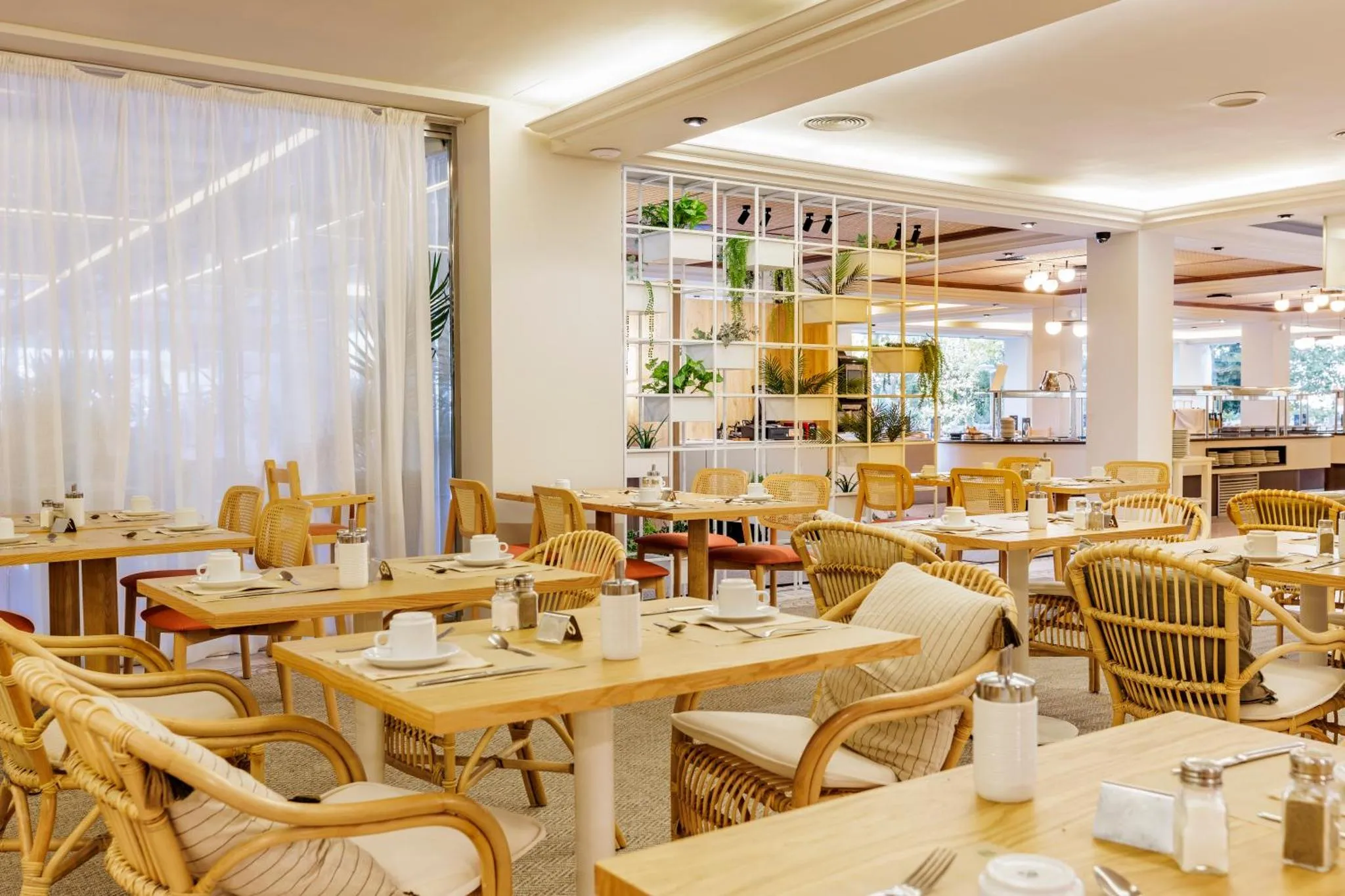 Une salle lumineuse avec des tables dressées pour le repas.