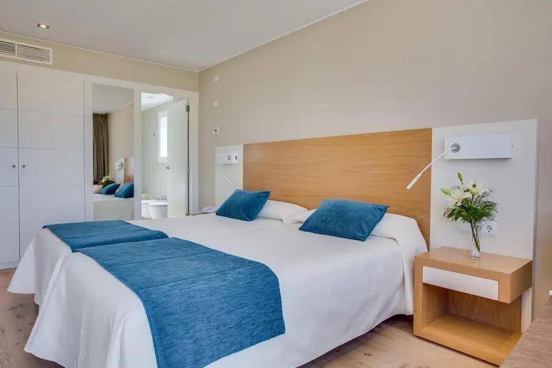 Une chambre lumineuse avec un grand lit recouvert d'une couverture bleue.