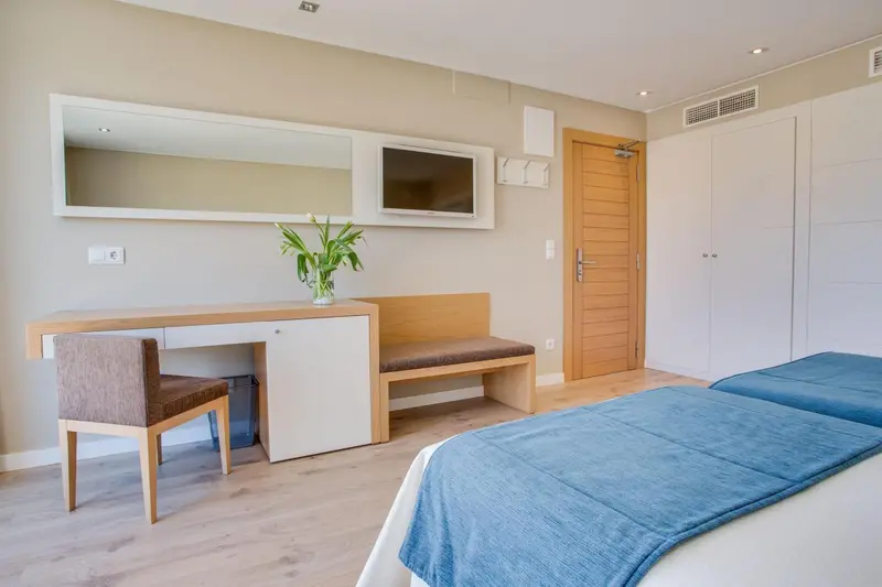 Une chambre lumineuse avec un bureau, une télévision et un lit.