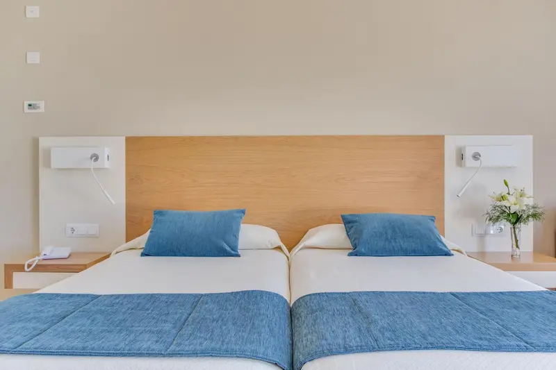 Une chambre avec deux lits simples et une décoration sobre.