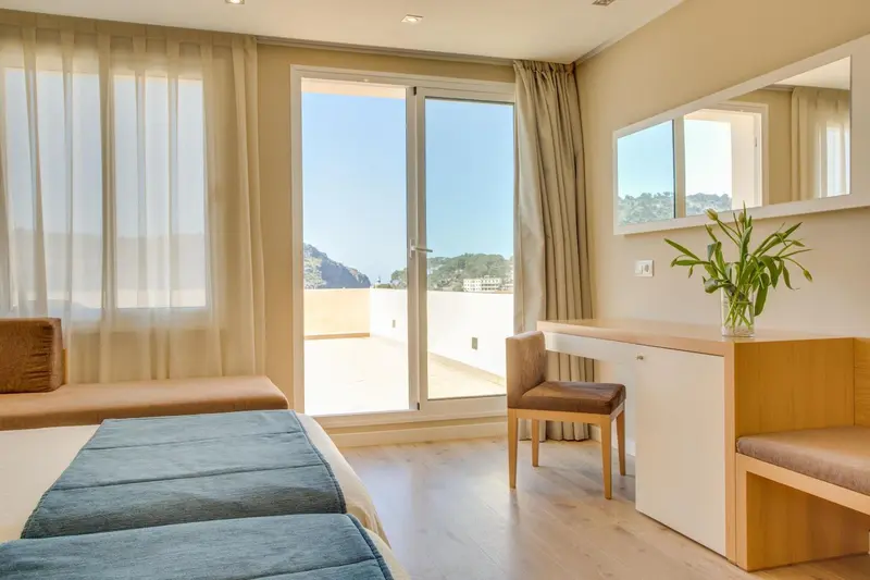 Une chambre lumineuse avec un bureau et un accès à une terrasse.