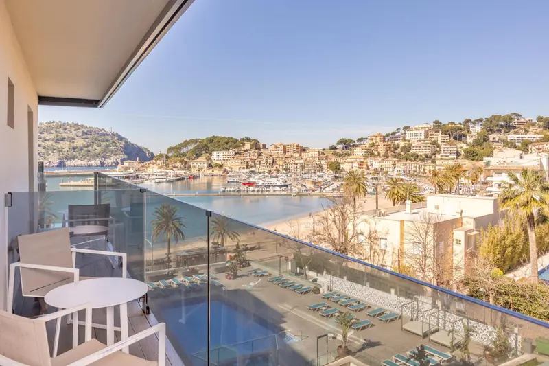 Vue d'une terrasse avec mobilier d'extérieur donnant sur une baie et une ville côtière.