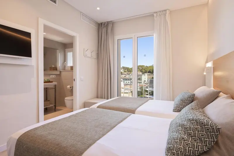 Une chambre lumineuse avec un lit double et un accès à un balcon.