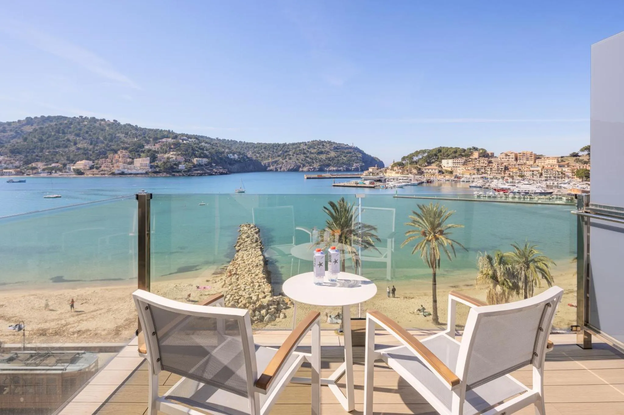 Deux fauteuils et une table basse sur une terrasse avec vue sur la mer et les collines.