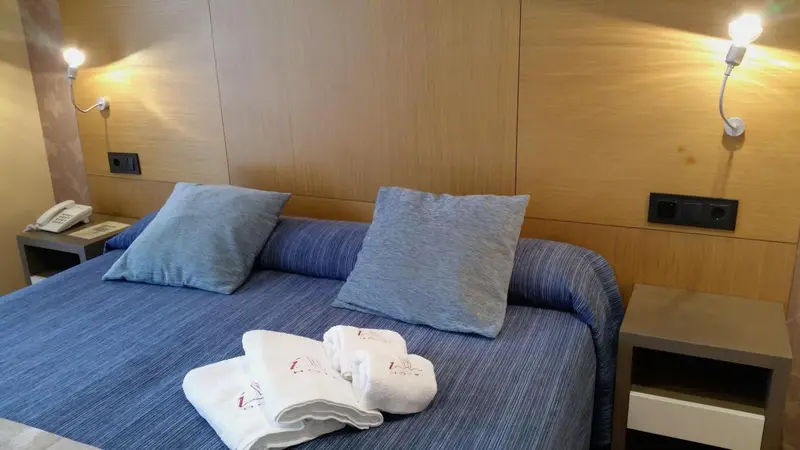 Une chambre avec un lit recouvert d'une couverture bleue et de coussins gris.