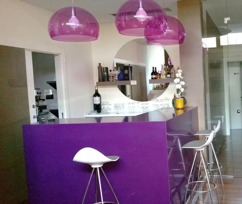 Un comptoir de bar moderne avec des tabourets et des bouteilles.