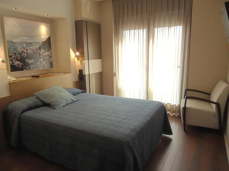 Une chambre lumineuse avec un grand lit et un fauteuil.