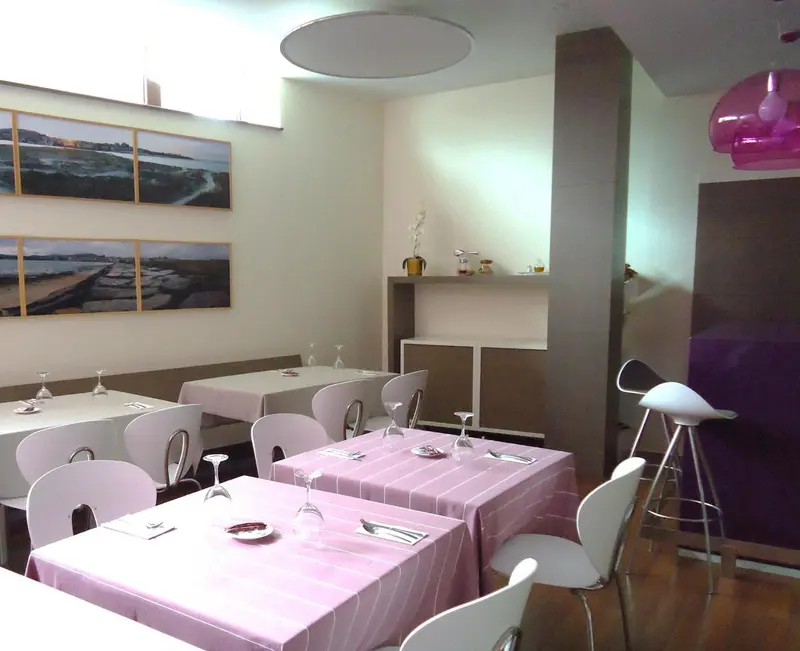 Une salle de restaurant lumineuse avec des tables nappées et des chaises blanches.