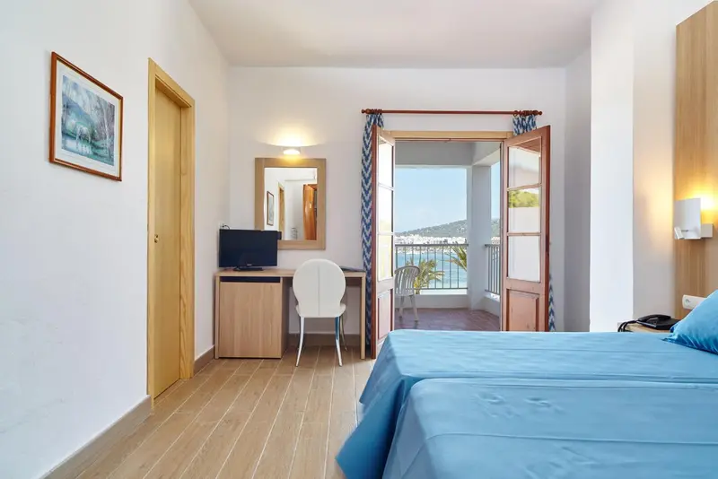 Une chambre lumineuse s'ouvre sur un balcon avec vue sur la mer.