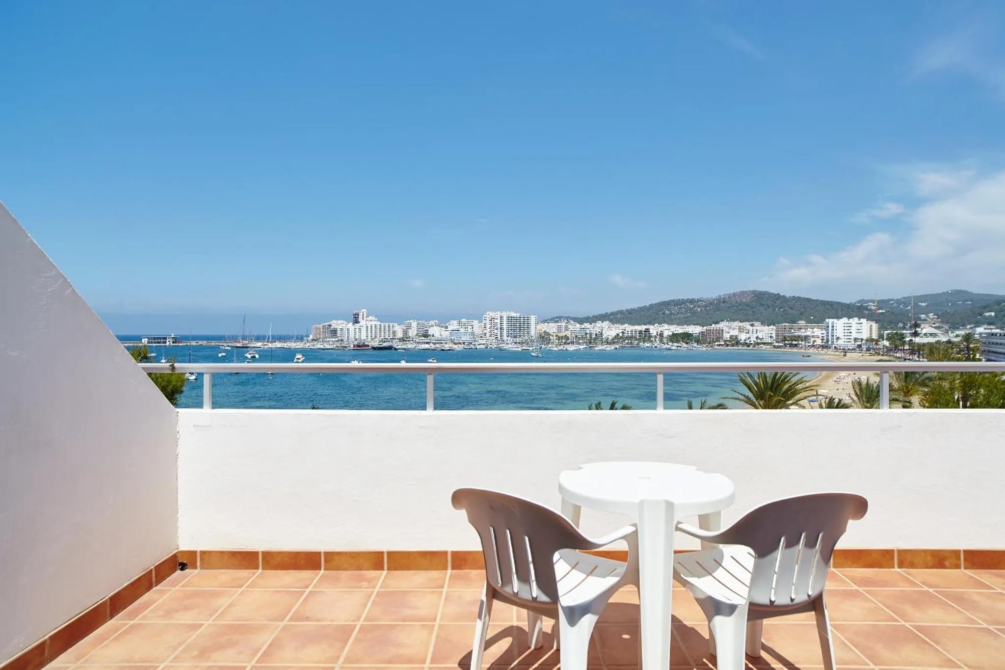 Vue d'une terrasse avec mobilier donnant sur la mer et la ville.