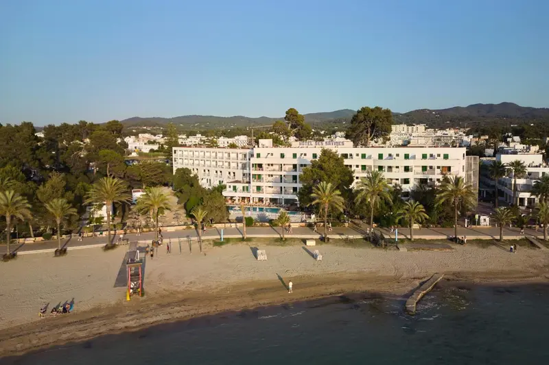 Vue aérienne d'un bâtiment blanc bordant une plage de sable.