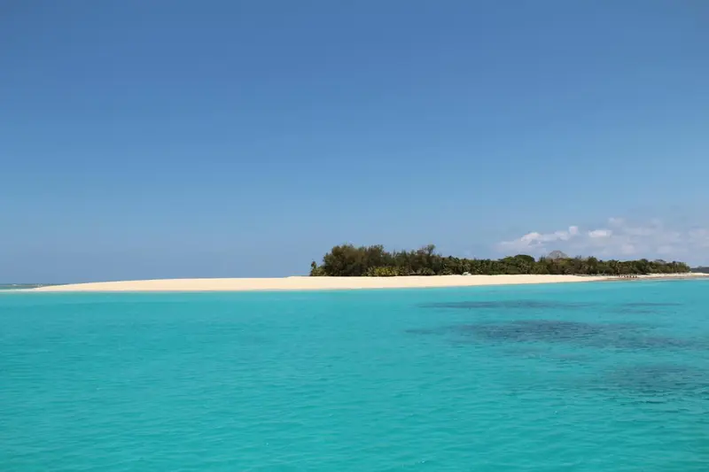 Île tropicale avec plage de sable blanc et eau turquoise.
