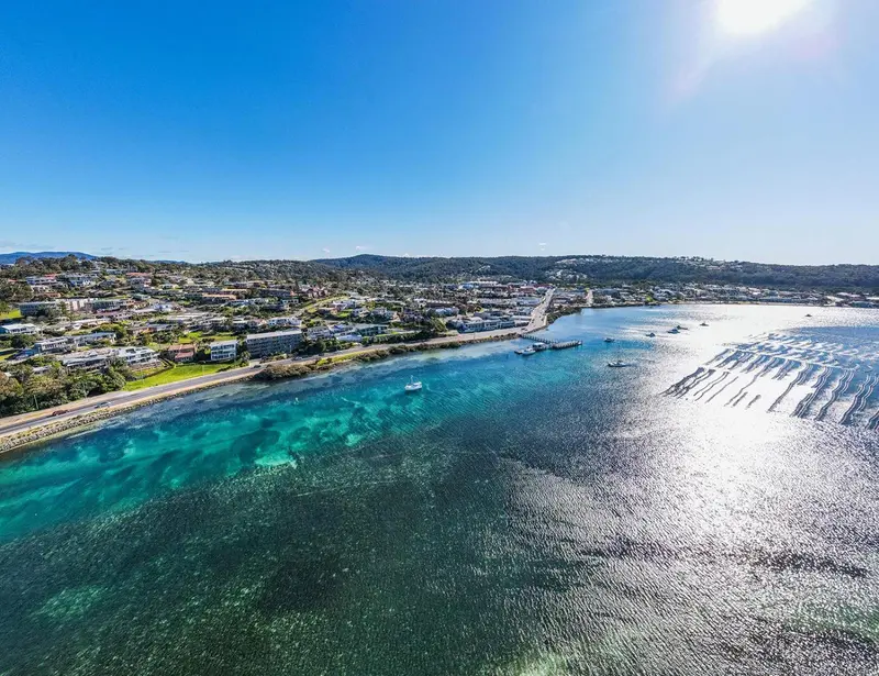 Vue aérienne d'une côte avec une ville et des bateaux dans une baie turquoise.