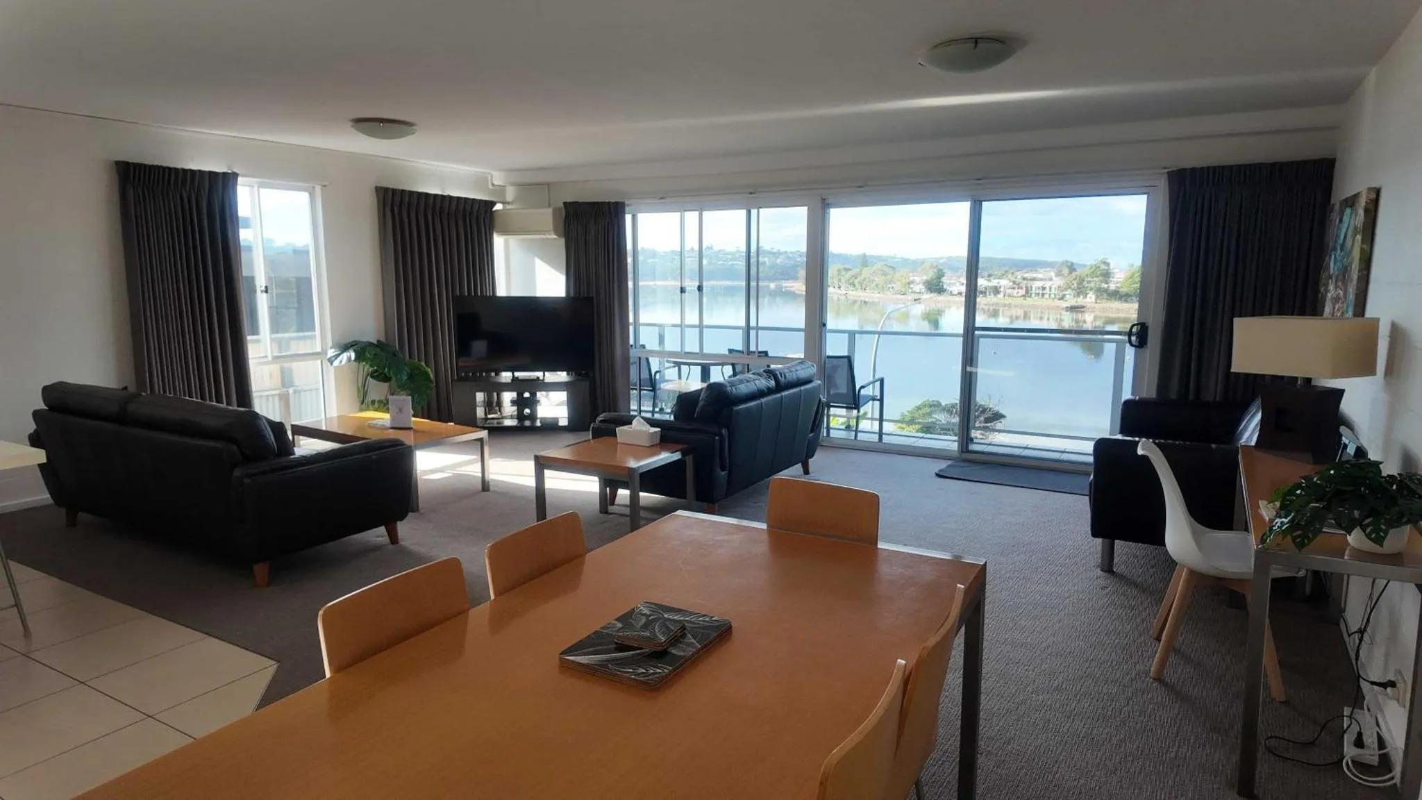 Espace de vie lumineux avec canapés, table basse et vue sur la mer.