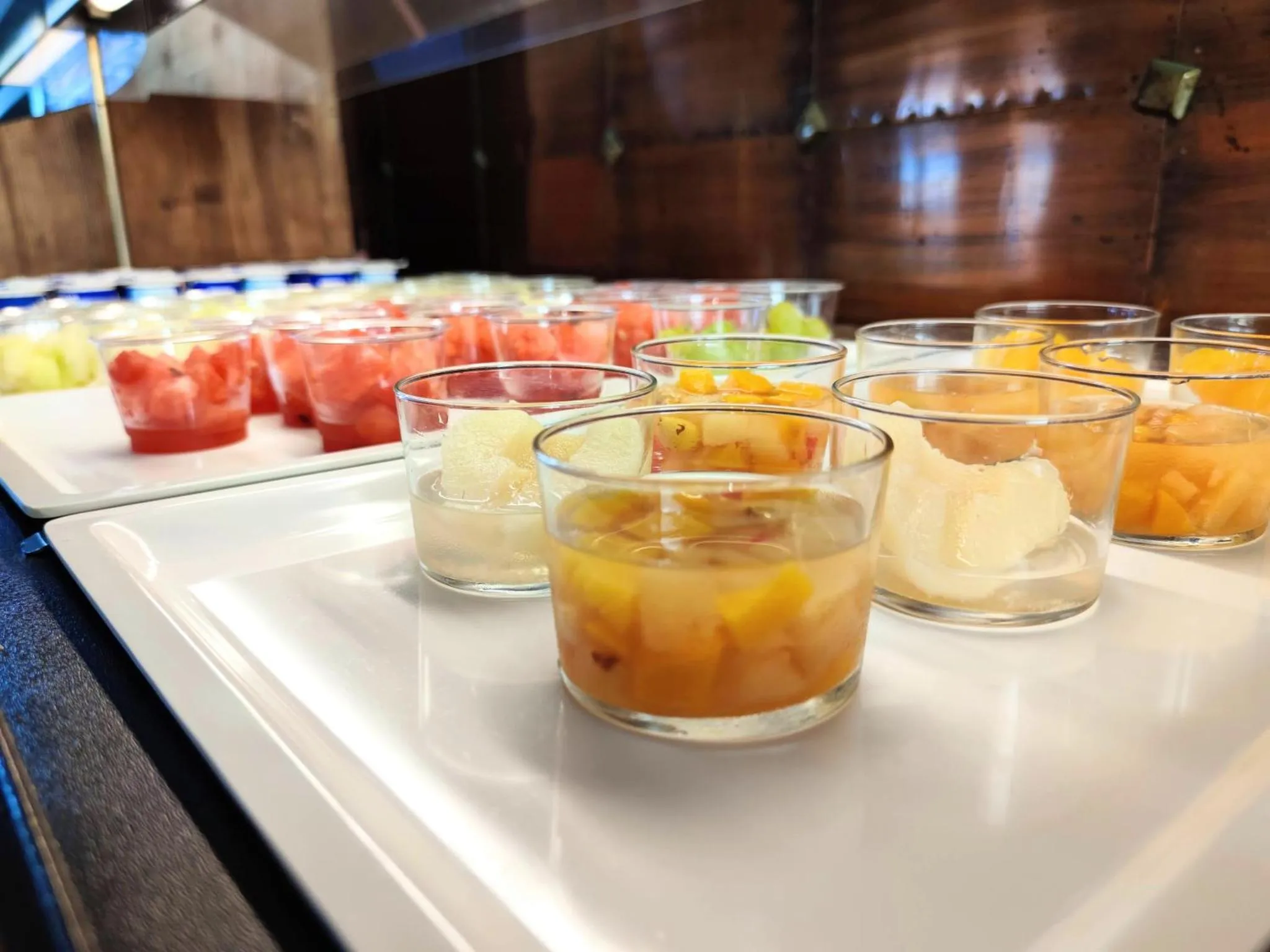 Assortiment de salades de fruits fraîches présentées dans des verrines.